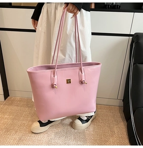 Close-up of pink oil wax leather tote bag with gold logo and stylish knotted shoulder strap