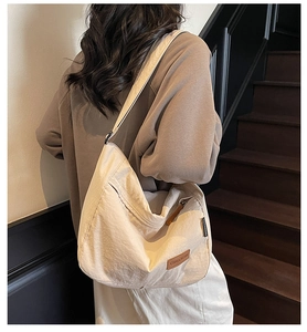Detailed close-up of a large beige tote bag with pleated texture and leather brand label