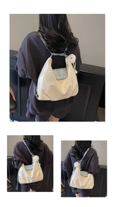Detail view of large cream hobo bag with light blue flap and plush charm on shoulder