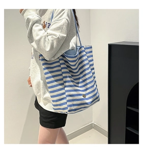 Close-up detail of blue and white striped canvas tote bag showing texture and dual handles