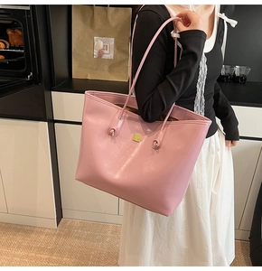 Detail of soft pink large capacity tote bag with gold metal accent and long shoulder straps