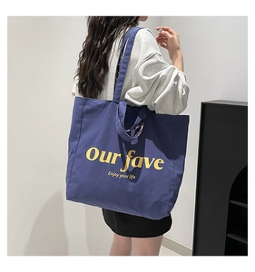 Macro detail of deep blue canvas tote bag with yellow text Our fave enjoy your life