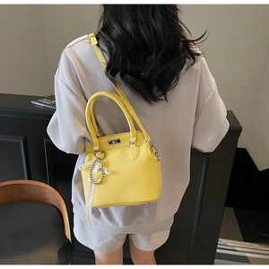 Detail of yellow pebbled leather Kelly bag with pearl charm on a waffled fabric outfit