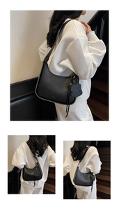 Detail of black lychee grain crescent bag with bear charm and tassel on shoulder
