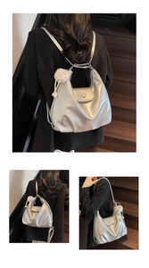Detailed view of silver tote bag with white plush charm and adjustable straps