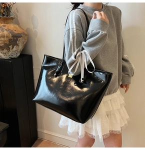 Detailed view of black oil wax leather tote bag with elegant white ribbon and gold hardware
