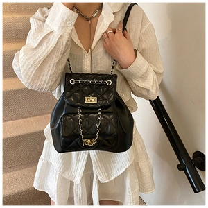 Close-up of black quilted chain backpack with elegant gold hardware and turn-lock detail