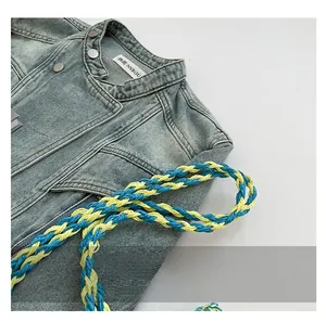 Détail d'une veste en jean bleu délavé avec poignée tissée contrastée jaune et bleu