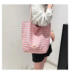 Detail of pink and white striped canvas tote bag with oval golden handmade metal label
