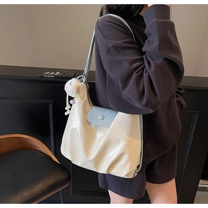 Détail du grand sac cabas en cuir beige avec boucle magnétique bleue et charm peluche