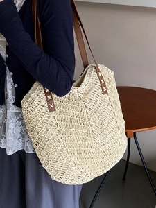 Minimalist cream woven straw tote bag with brown leather straps for beach holidays