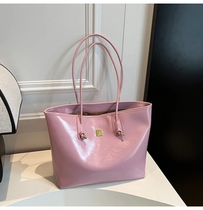 Detail of pink oil wax leather tote bag featuring golden logo plate and knotted handles