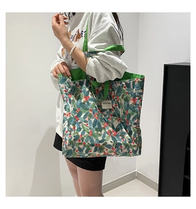Detail of botanical print tote bag with green handles and OUR FAVE woven label