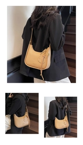 Close-up of light brown lychee grain leather underarm bag with cute bear charm