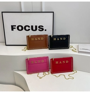 Detailed view of woven leather handbags with metal studs and gold HAND lettering