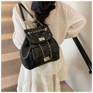 Quilted leather backpack with gold chain straps worn by model on white outfit