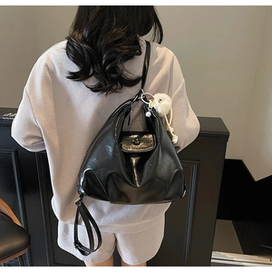Détail d'un sac hobo en cuir PU brillant noir avec une petite poche et un pendentif peluche