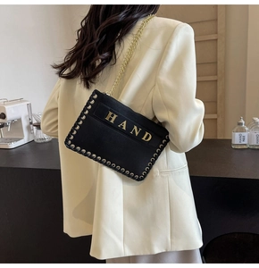 Close-up of black leather crossbody bag with gold HAND hardware and rivet woven details