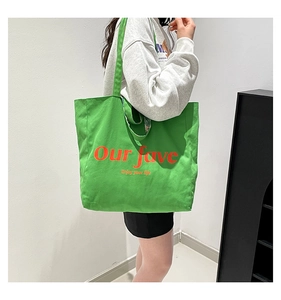 Close-up of green canvas tote bag with Our Fave orange text and yellow slogan