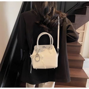 Detail of white lychee texture handbag with silver twist lock and pearl bow accessory