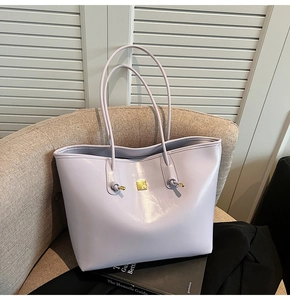 Detail of lavender oil wax leather tote bag with gold logo on a woven chair