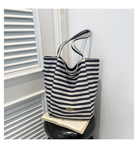 Detail of navy striped canvas tote bag showing handmade metal tag and thick texture