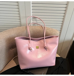 Detail of light pink glossy tote bag featuring gold metal hardware and knot handle design