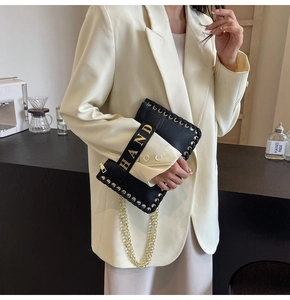 Close-up of black litchi grain envelope bag with gold metal eyelets and chain strap