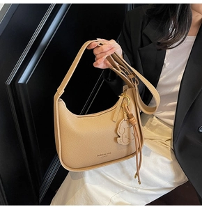 Detail of khaki lychee grain shoulder bag with dog charm and tassel zipper pull