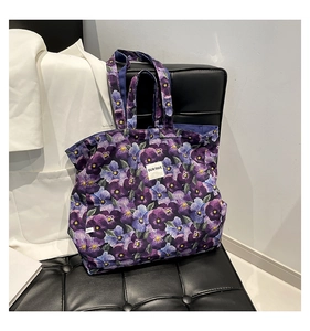 Detail of floral canvas tote bag with purple pansy print and OUR FAVE woven label