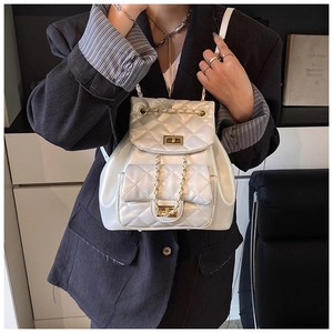 Detail view of a white quilted backpack with golden chain straps on a female model