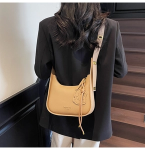 Detail of light brown lychee grain underarm bag with a cute dog-shaped leather charm