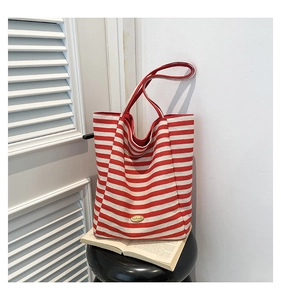 Detail of red and white striped knit tote bag with handmade label on indoor setting