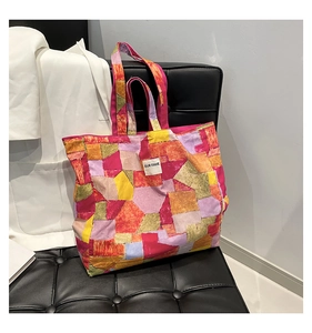Detail of colorful geometric canvas tote bag with embroidered 'OUR FAVE' label on leather sofa