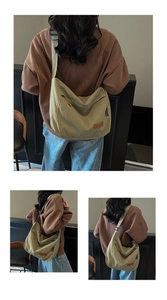 Detail of khaki canvas tote bag with brown leather logo and wide crossbody strap