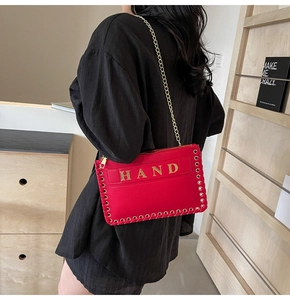 Chic red woven envelope bag with gold chain strap worn by model in lifestyle setting