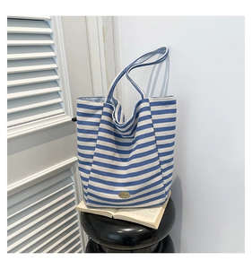 Detailed macro of blue and white striped canvas tote bag with elegant metal logo plate