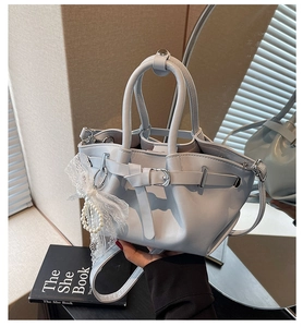 Close-up of pleated bucket bag with pearl lace bow detail and silver hardware accents