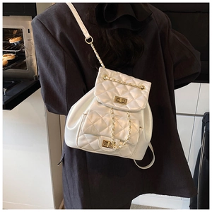 Detail of white quilted mini backpack featuring gold metal clasp and chain strap