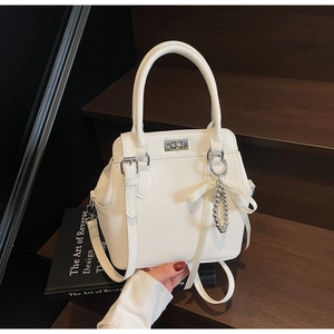 White lychee leather trapezoid handbag with silver twist lock and silk ribbon charm