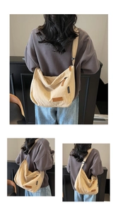 Detail view of the beige canvas tote bag showing the leather logo and adjustable shoulder strap