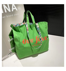 Macro shot of large green canvas tote bag with red script print and floral interior lining