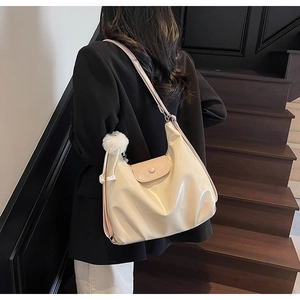 Détail d'un grand cabas crème avec rabat rose et breloque en peluche sur un modèle