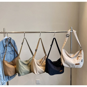 Multiple colors of large capacity canvas crossbody tote bags displayed on a rack