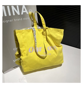 Detail of yellow canvas tote bag featuring purple Our Love lettering and floral lining