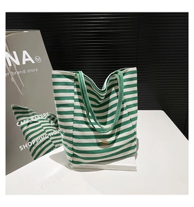 Detailed close-up of green striped canvas tote bag with gold brand emblem and handles