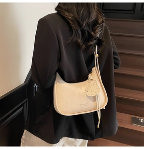 Detail of beige lychee pattern faux leather bag with fashion text and cute bear charm