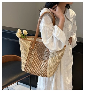 Detail of hollow woven straw tote bag with contrast stitching and brown leather handle