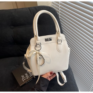 Detail of white lychee pattern crossbody bag with silver twist lock and ribbon charm