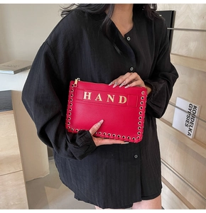 Detail of red pebbled leather envelope clutch with HAND gold print and metal grommets